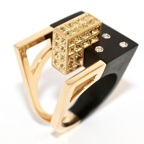 Anello Urban Contact, ebano e oro 18 kt rivestito di zaffiri gialli e diamanti incastonati - La contaminazione tra il pregiato  Ebano e il prezioso Oro 18 kt, rivestito  di Zaffiri gialli, simboleggia l’armonia  delle moderne costruzioni dall’aspetto  austero ed elegante, inserite nel  green-mood circostante ridisegnato  dall’uomo sottoforma di accoglienti  giardini dove la natura si risveglia nei preziosi Diamanti incastonati.