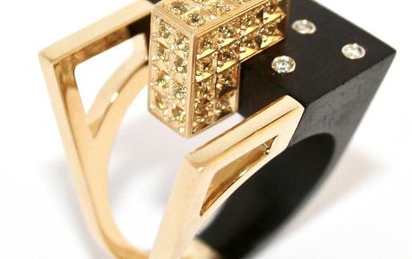 Anello Urban Contact, ebano e oro 18 kt rivestito di zaffiri gialli e diamanti incastonati - La contaminazione tra il pregiato  Ebano e il prezioso Oro 18 kt, rivestito  di Zaffiri gialli, simboleggia l’armonia  delle moderne costruzioni dall’aspetto  austero ed elegante, inserite nel  green-mood circostante ridisegnato  dall’uomo sottoforma di accoglienti  giardini dove la natura si risveglia nei preziosi Diamanti incastonati.